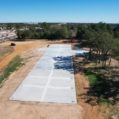 side aerial view of concrete slab foundation for 50x235 metal building near Columbus Texas